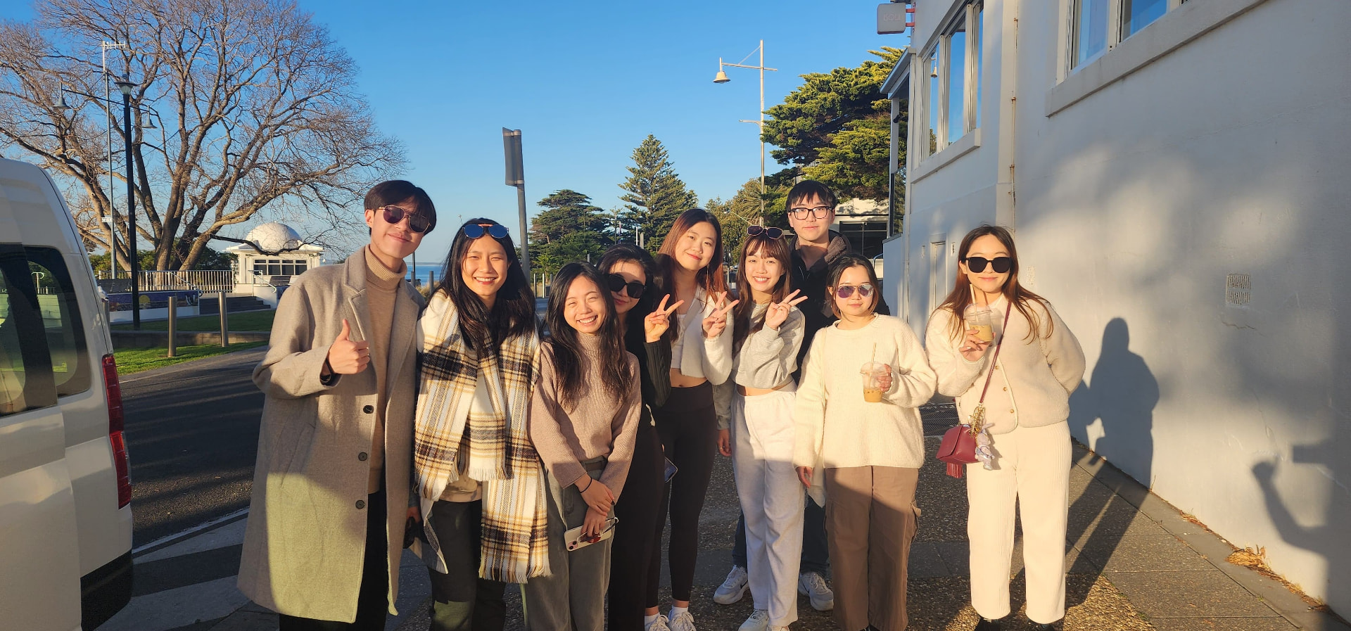 Bloom of Youth alumni group photographed together on a sunny street by the waterfront in Australia