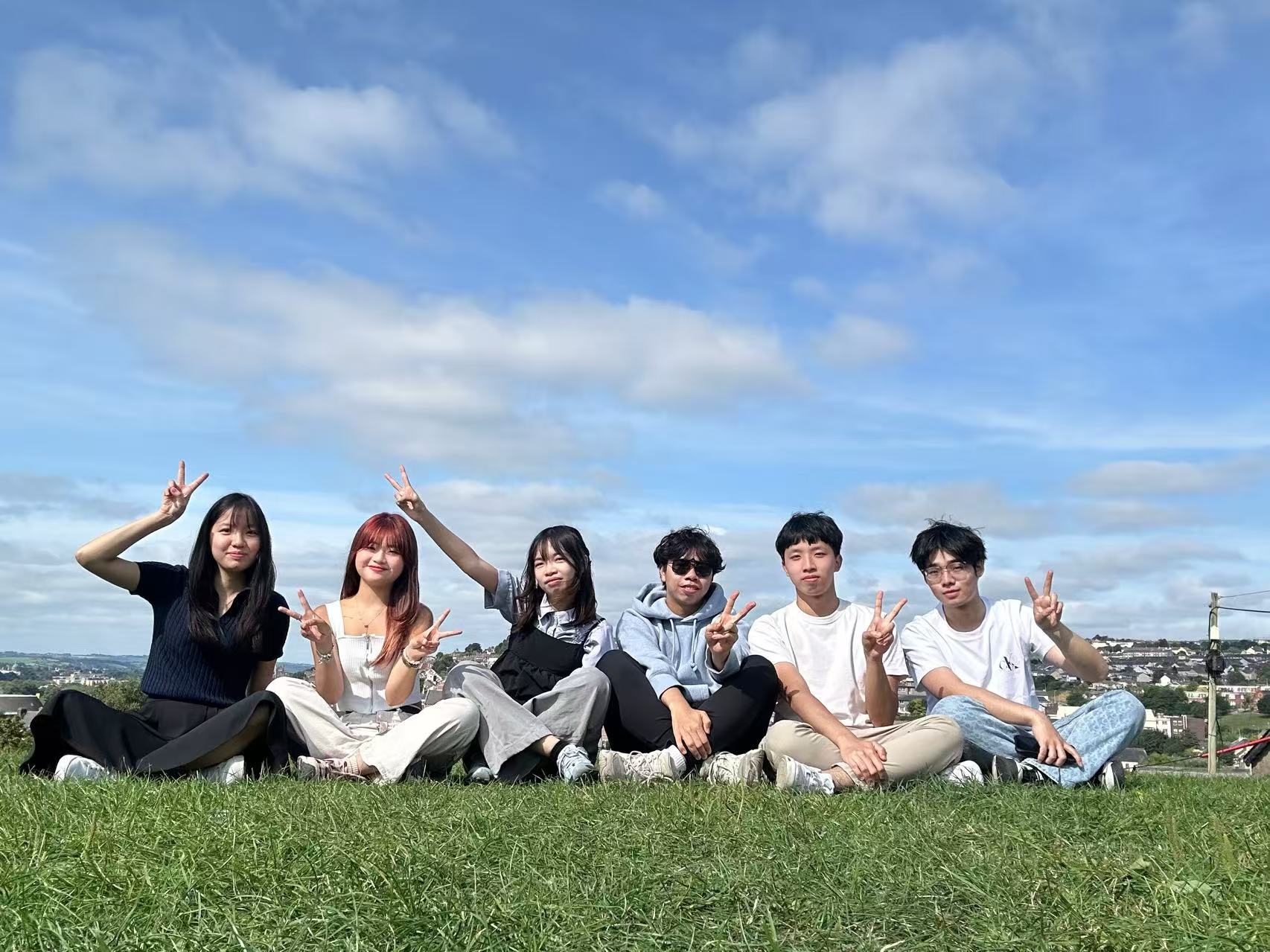 Interns sitting on a grassy hillside overlooking Cork, Ireland