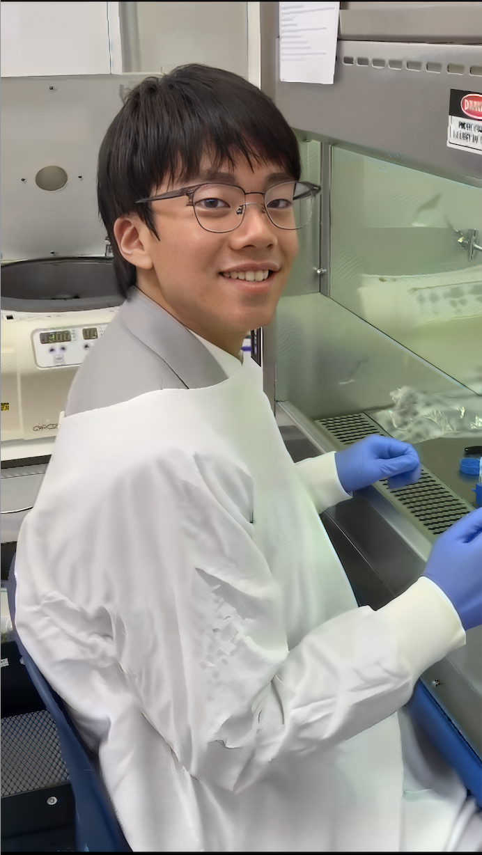Alumnus in a lab coat working at a fume hood during a science internship